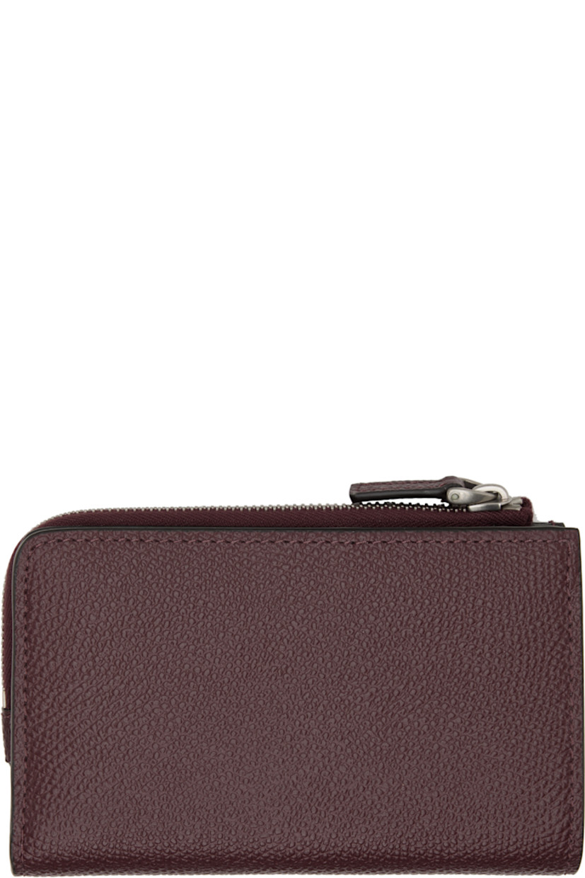 Pebble-grained calfskin wallet.

· Logo hardware and zip coin compartment at face
· Press-stud closure
· Eight card slots at interior 
· Two patch pockets and one note slot
· Canvas lining 
· Silver-tone hardware 
· H3.25" x W5" x D0.75"

Supplier color: Rosewood