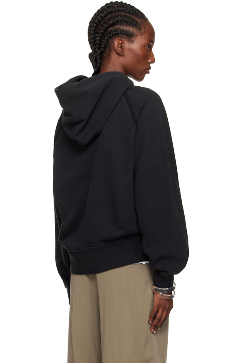 Oversized garment-dyed organic cotton fleece hoodie.

· Drawstring at hood
· Rib-knit hem and cuffs
· Exposed seam at raglan sleeves
· Detachable felted logo patch at sleeve

Supplier color: Black