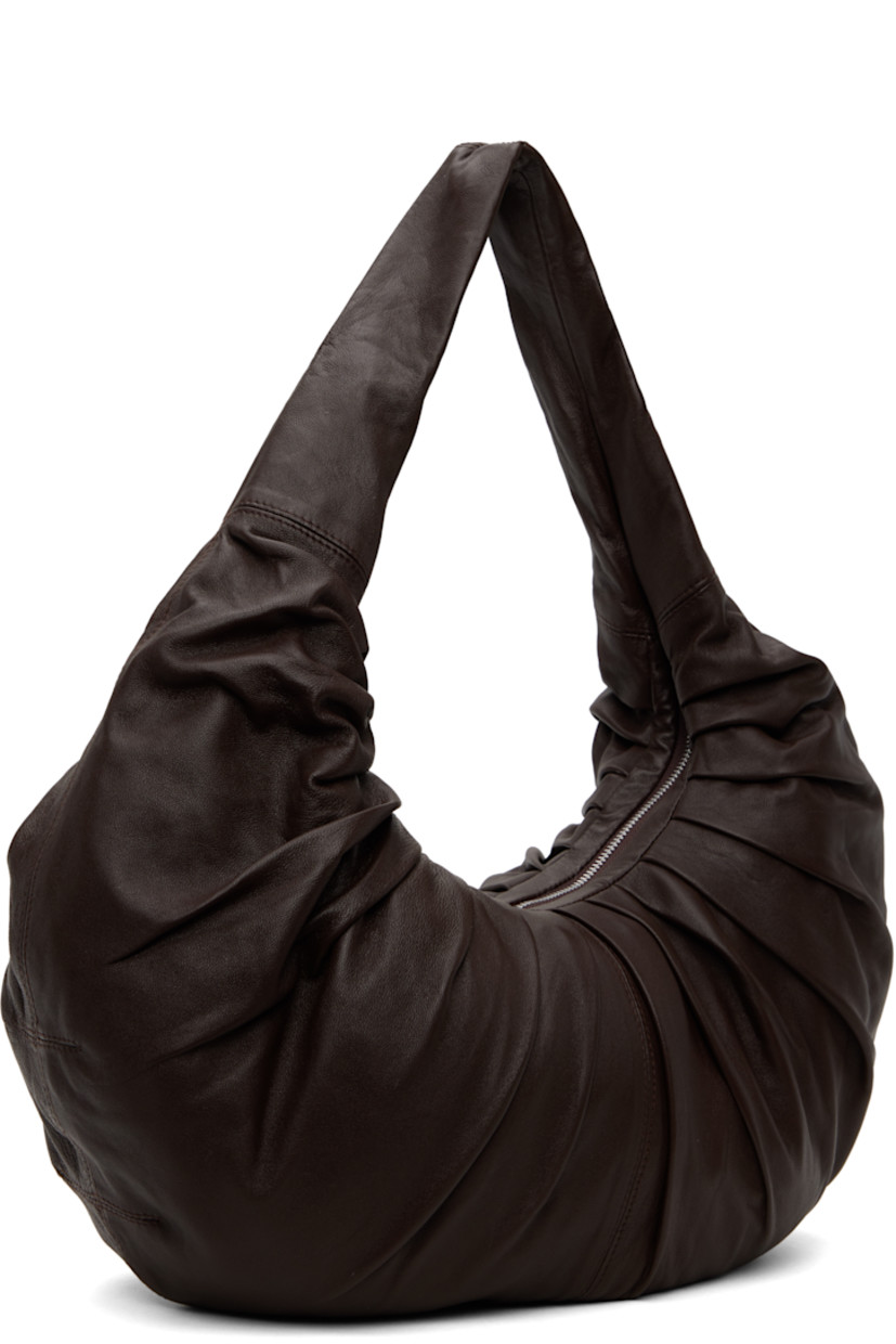 Grained goatskin shoulder bag in brown.

· Ruching throughout
· Integrated shoulder strap
· Zip closure
· Zip pocket and patch pockets at interior
· D-ring at interior
· Twill lining
· H12.5" x W21" x D3.5"

Supplier color: Wood