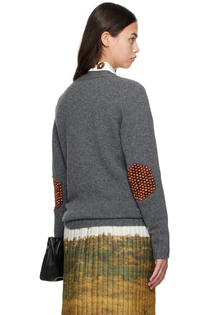 Knit wool cardigan.

· Rib-knit Y-neck, hem, and cuffs
· Button closure
· Patch pockets at front
· Wooden beading at elbows

Supplier color: Grey/Brown