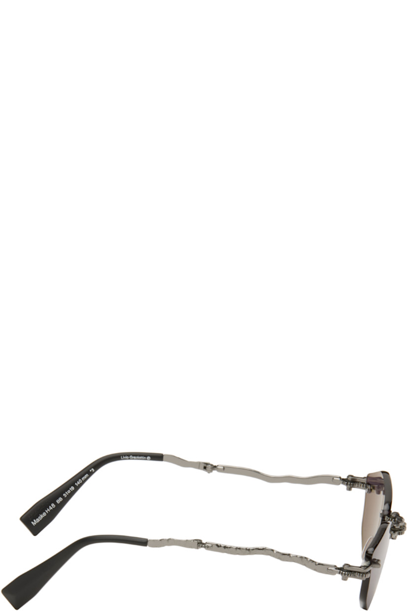Handcrafted collapsible hexagonal metal-frame sunglasses.

· Spur gears at hinges
· Engraved detailing throughout
· Gray lenses
· Adjustable metal nose pads
· Sculptural arms
· Acetate temple tips
· Includes case
· Size: 51.19 140

Supplier color: Gunmetal