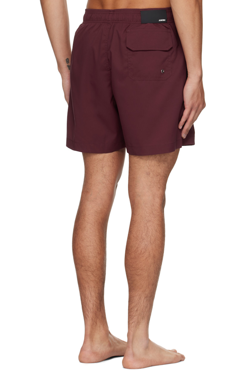 Taffeta swim shorts. 

· Drawstring at elasticized waistband
· Three-pocket styling
· Logo and text printed at front 
· Rubber logo patch at back waistband
· Grommet at back pocket 
· Full mesh brief-style lining

Supplier color: Wine