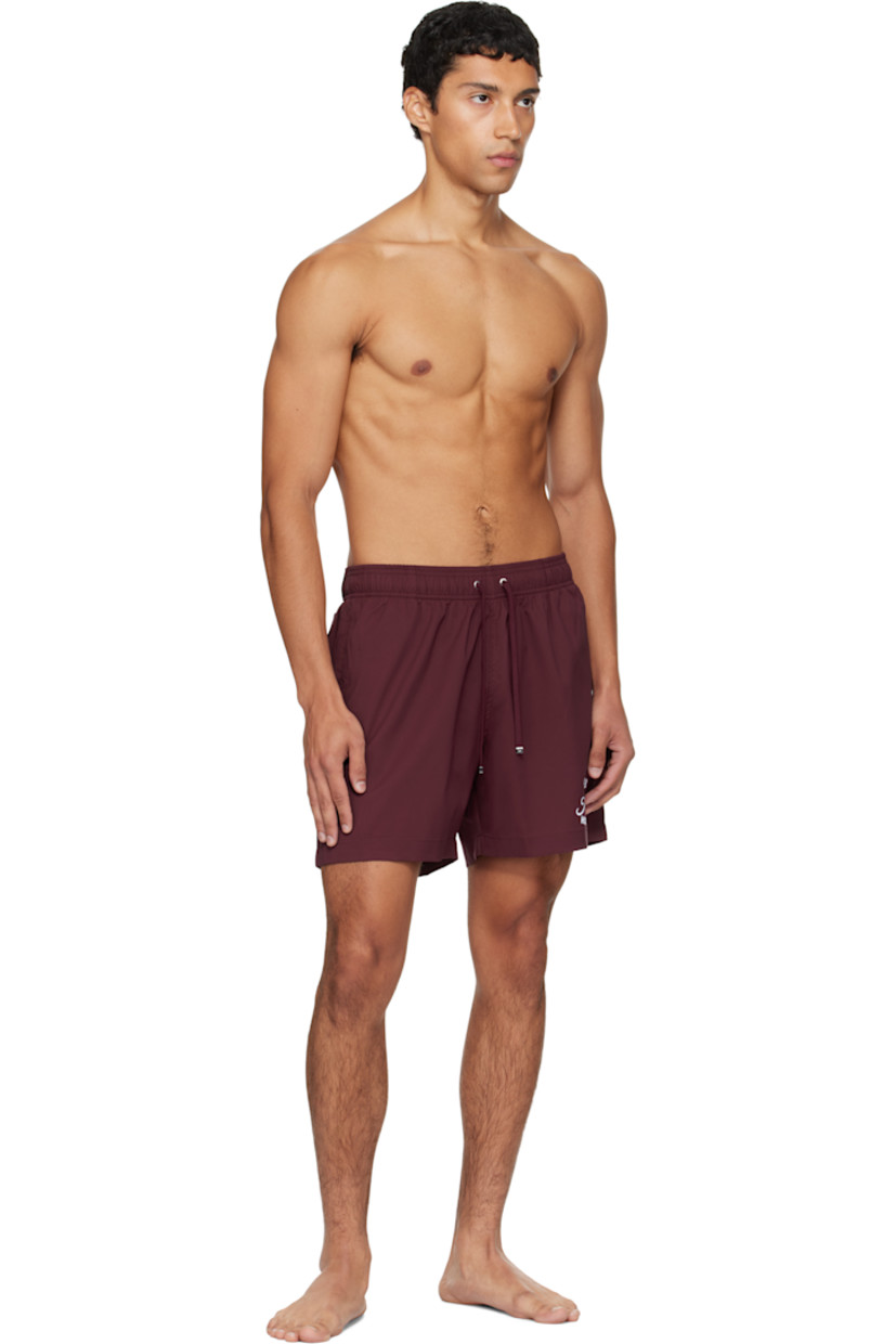 Taffeta swim shorts. 

· Drawstring at elasticized waistband
· Three-pocket styling
· Logo and text printed at front 
· Rubber logo patch at back waistband
· Grommet at back pocket 
· Full mesh brief-style lining

Supplier color: Wine