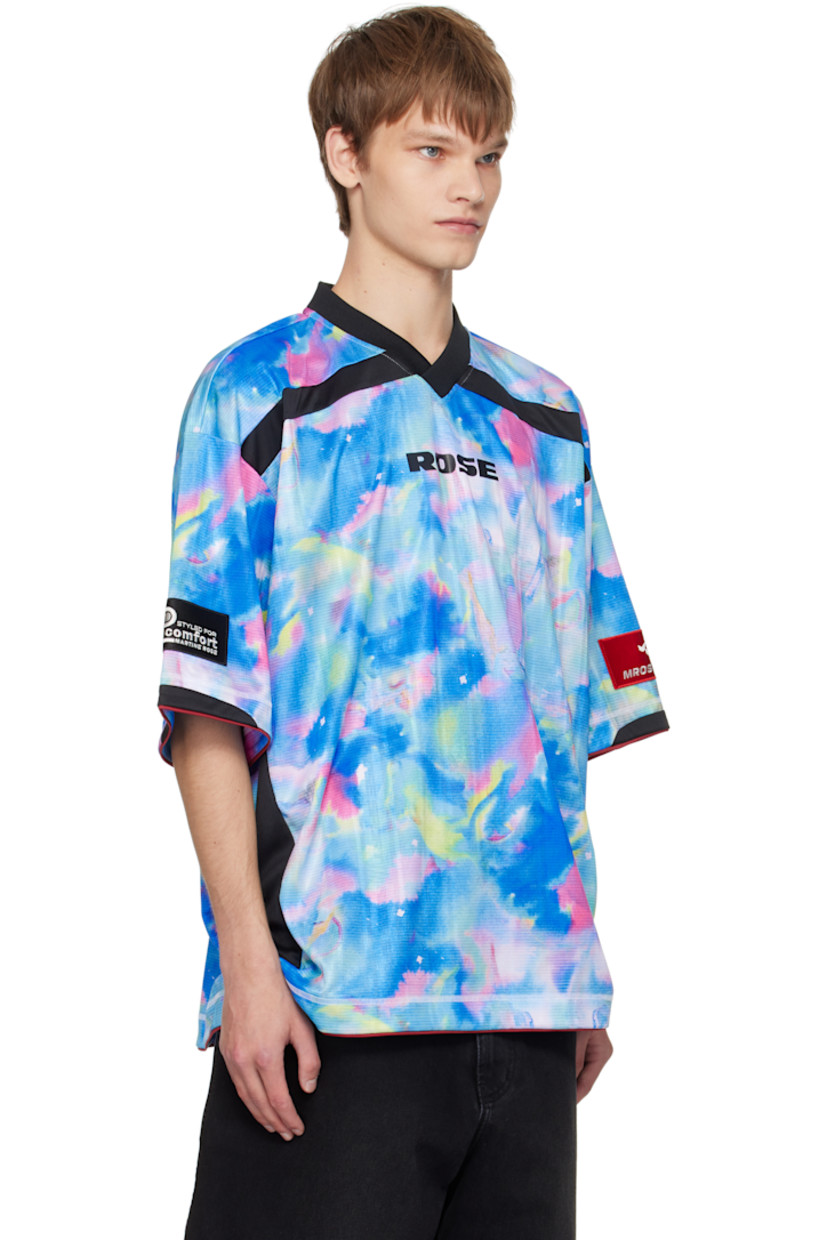 Jersey T-shirt.

· Graphic pattern printed throughout
· Rib-knit V-neck
· Logo printed at chest and back
· Piping at hem and cuffs
· Logo patch at cuff
· Text flocked at back

Supplier color: Blue watercolour