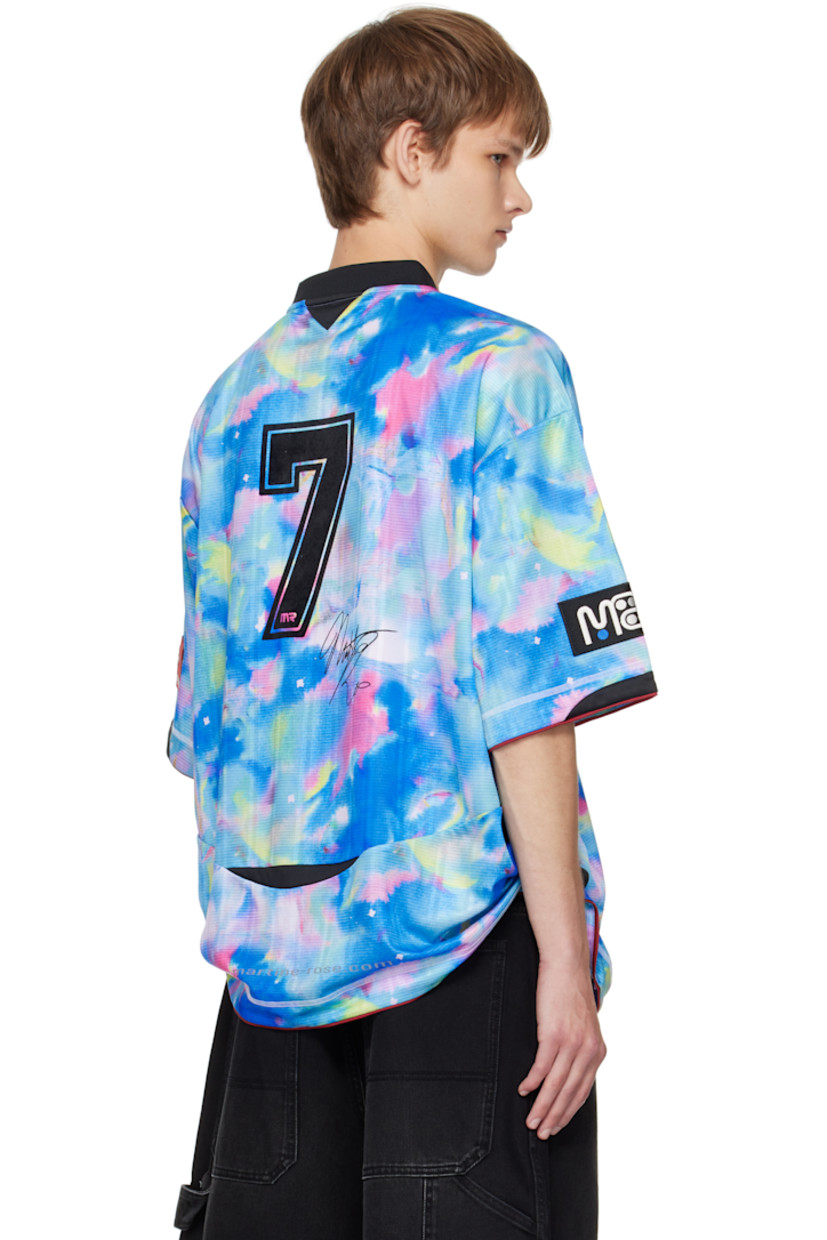 Jersey T-shirt.

· Graphic pattern printed throughout
· Rib-knit V-neck
· Logo printed at chest and back
· Piping at hem and cuffs
· Logo patch at cuff
· Text flocked at back

Supplier color: Blue watercolour
