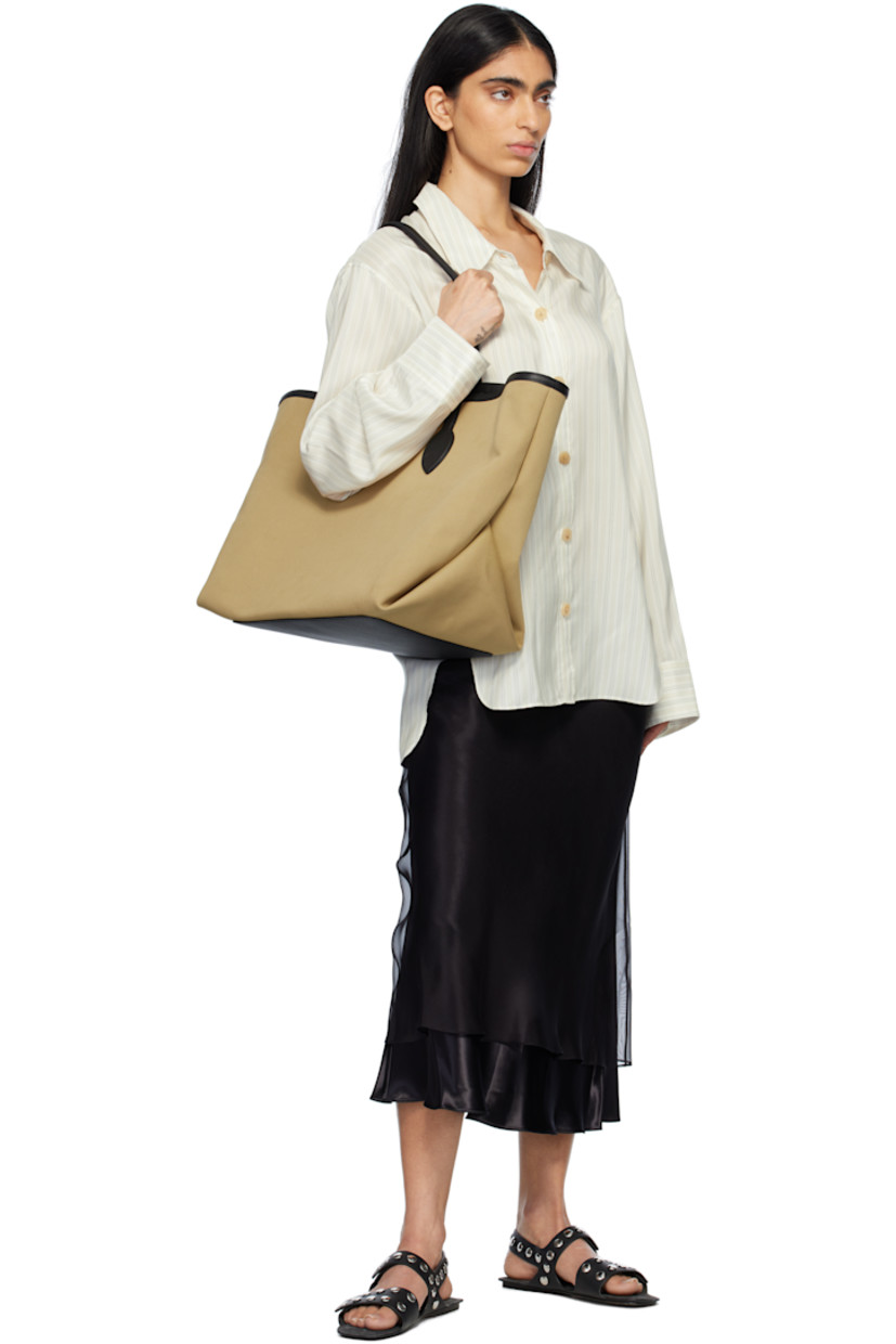 Lightweight canvas tote in taupe.

· Pebble-grained calfskin trim in black throughout
· Fixed twin shoulder straps
· Logo stamp at face
· Toggle closure 
· Patch pockets at interior 
· Unlined
· H13" x W22" x D10"

Supplier color: Honey canvas/Black leather