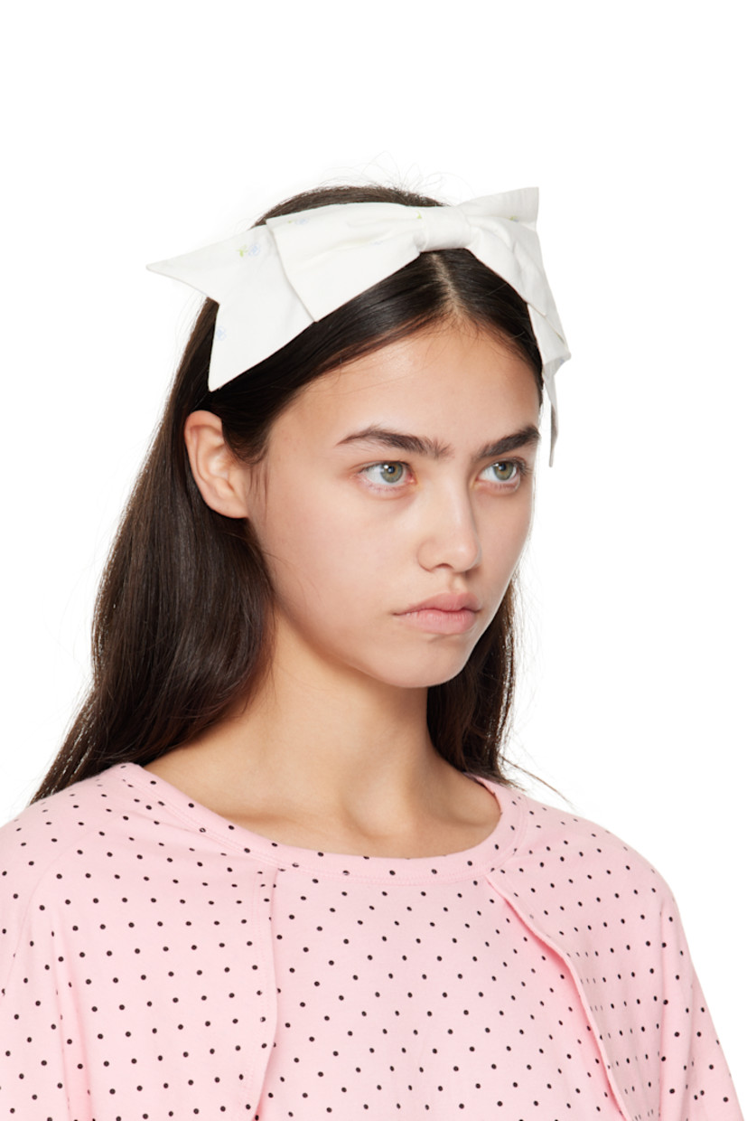 Woven headband.

· Floral pattern printed throughout
· Bow appliqué at crown

Supplier color: Tissue paper