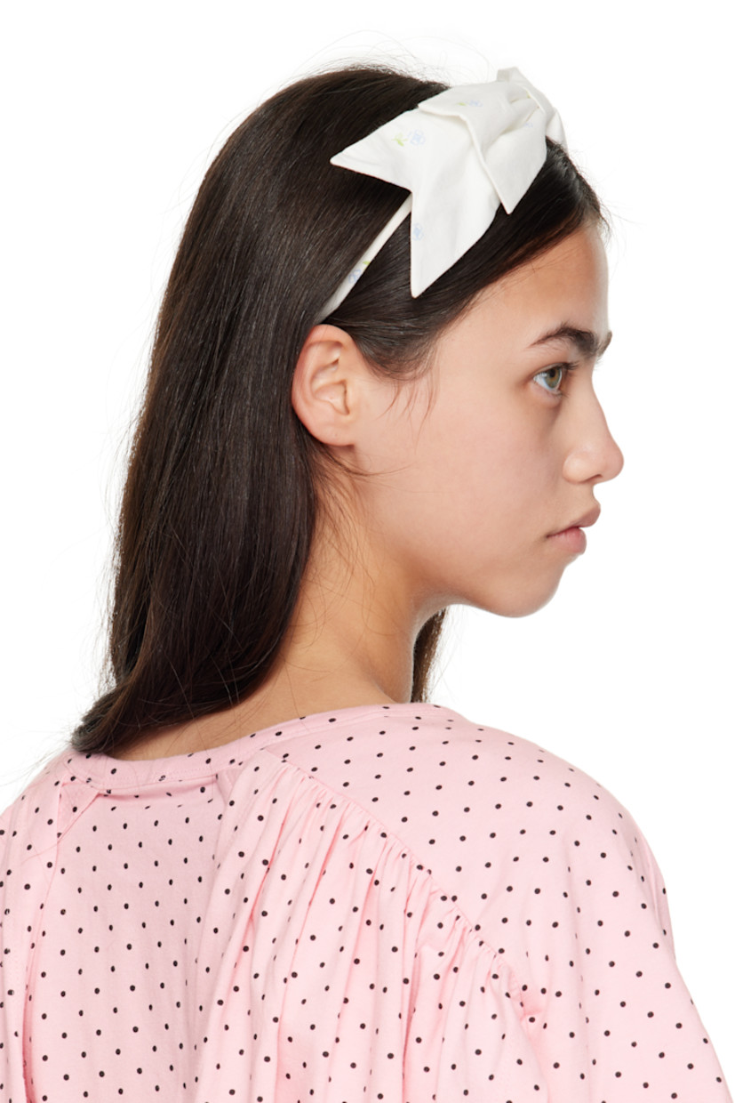 Woven headband.

· Floral pattern printed throughout
· Bow appliqué at crown

Supplier color: Tissue paper