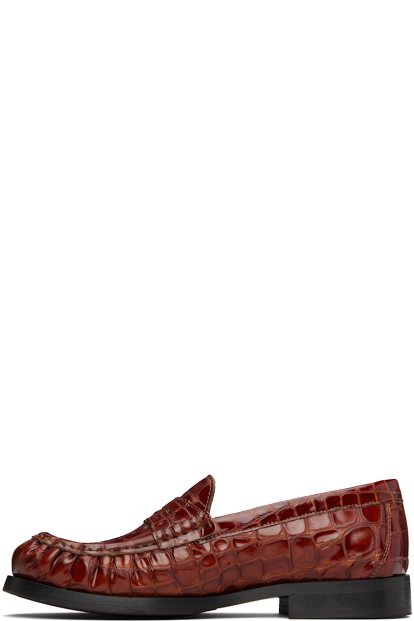 Croc-embossed leather loafers.

· Moc toe
· Strap with cutout at vamp
· Buffed leather lining
· Stacked leather heel with rubber injection
· Leather sole with rubber injection

Supplier color: Brown croco