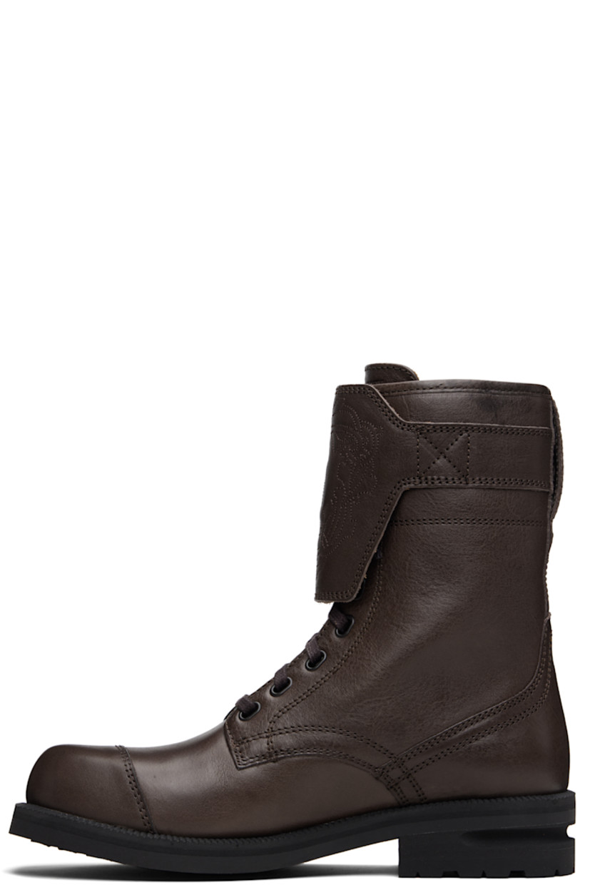 Mid-calf grained leather boots.

· Lace-up closure
· Logo graphic embroidered at vamp
· Logo embossed at tongue
· Pin-buckle strap at outer side
· Serrated edge at welt
· Treaded Vibram® rubber sole

Supplier color: Dark brown