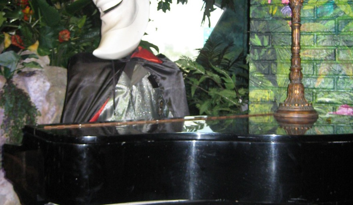 Woman playing a grand piano with "play me" sign