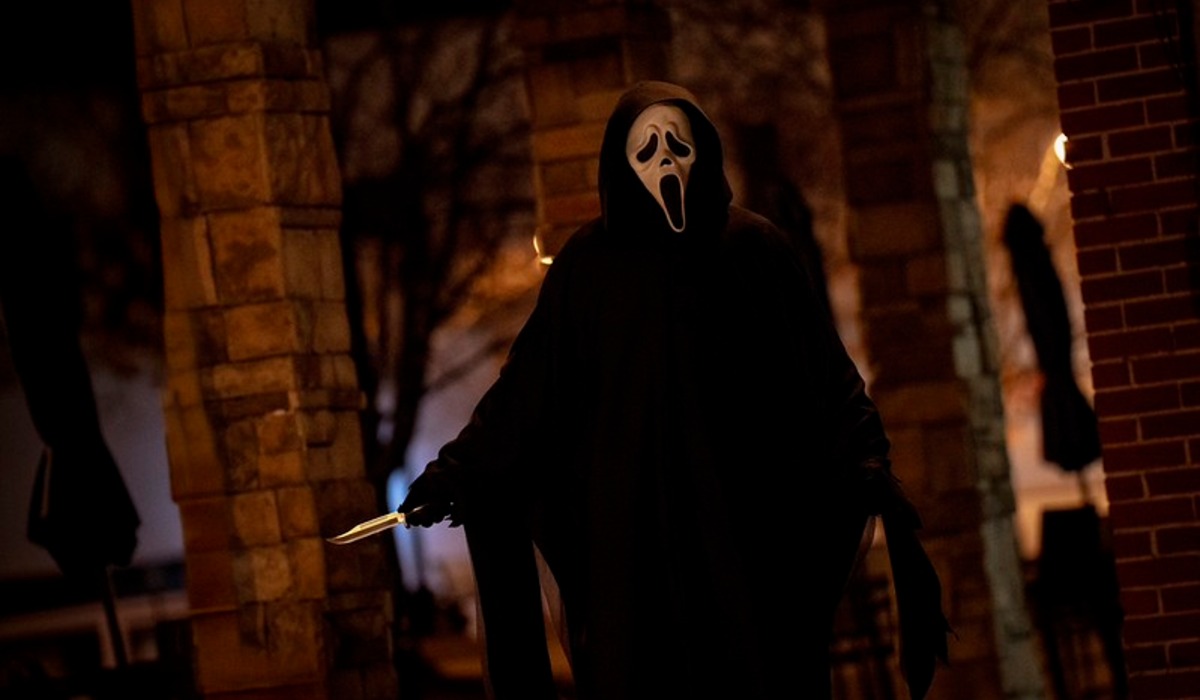 a man wearing a mask standing in front of a log