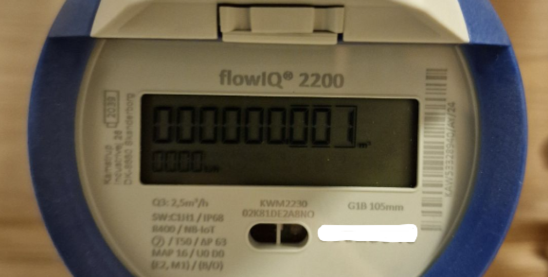 Rund vannmåler med hvit forside med talldisplay og blå kant rundt