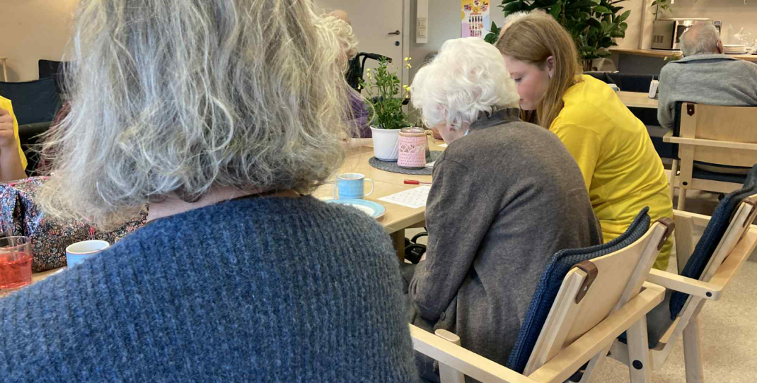 to eldre mennesker som sitter ved et bord sammen med en ung jente