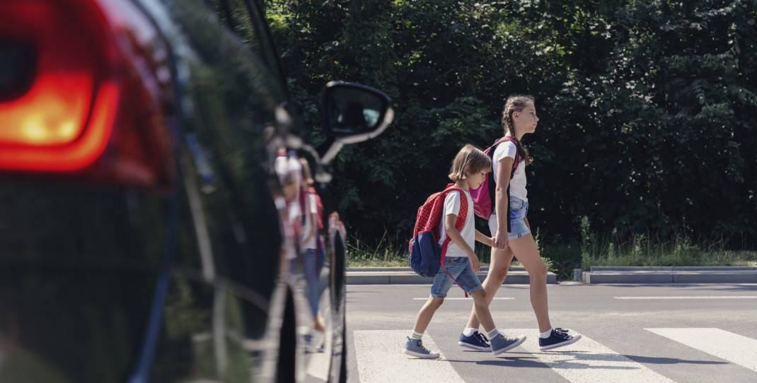 to barn som går over en fotgjengerovergang mens en bil står og venter