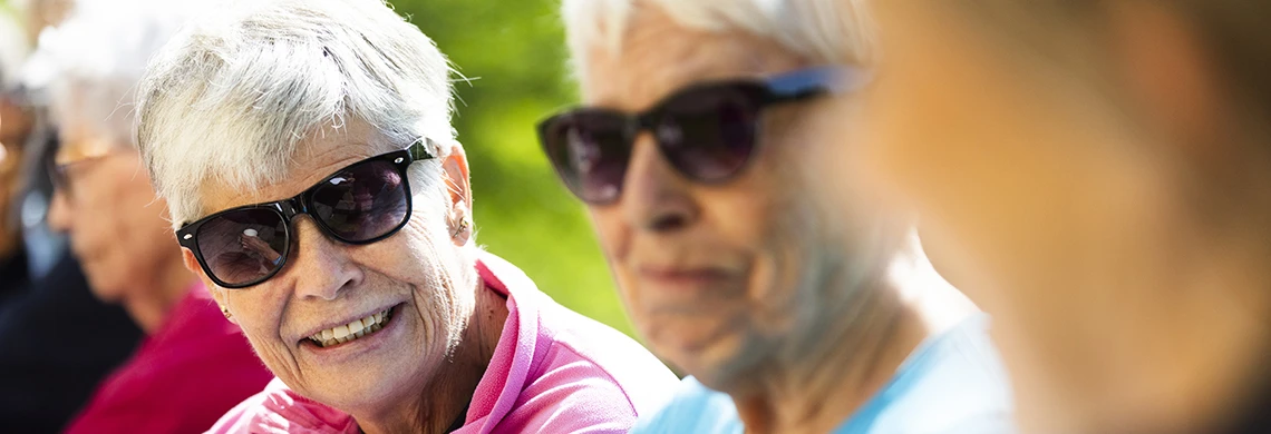 Eldre damer med solbriller som sitter og snakker