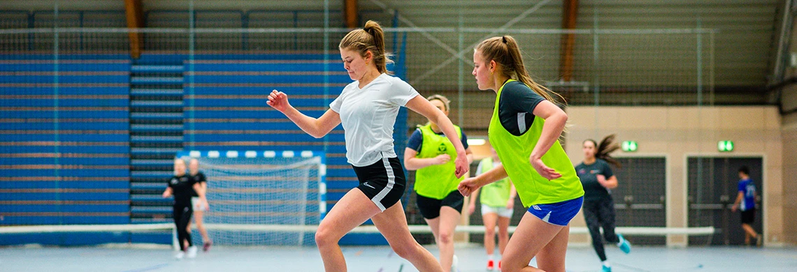 Damer som sparker fotball inne i en idrettshall