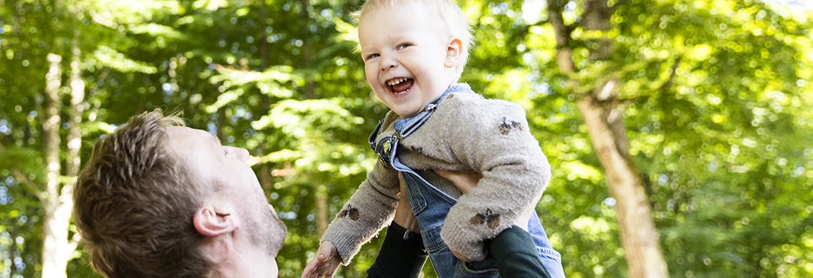 Mann som holder liten gutt opp i været