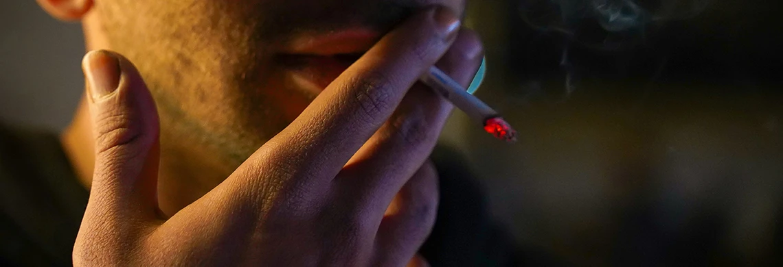 Mann som røyker en sigarett