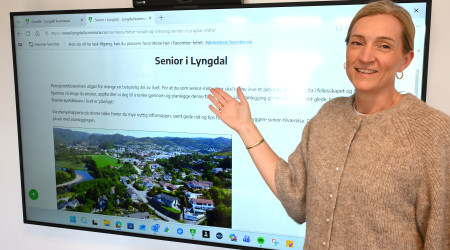 Ingunn Skretting foran storskjerm som viser nettsiden Senior i Lyngdal