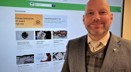 Ronny Bjørnevåg foran storskjerm som viser kommunens nye hjemmeside