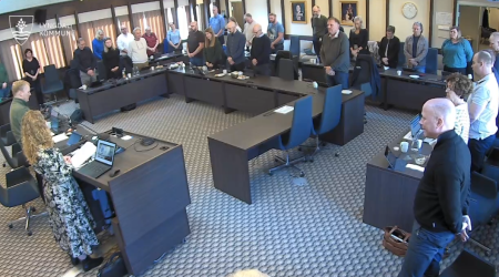 Bilde av kommunestyret som har reist seg for ett minutts stillhet