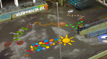 Dronefoto av fargerike tegninger på uteplassen ved Å barneskole