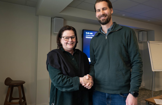 Fylkesdirektør Toril Eeg og direktør for prosjektgjennomføring i HENT AS, Erik Tveit, gratulerer hverandre med kontrakt i et møterom