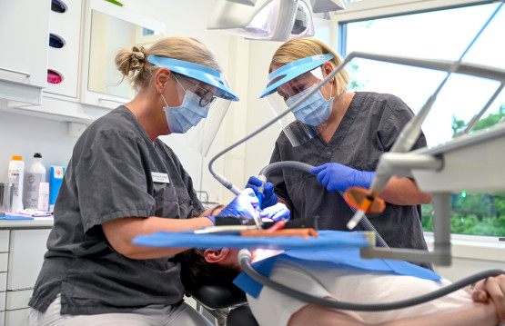 To tannleger behandler en pasient på en tannklinikk