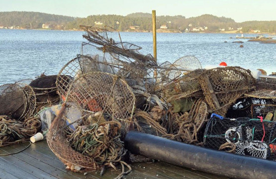 Bildet viser en brygge med en kontainer, og en haug med teiner, tau og ulike fiskeredskaper.