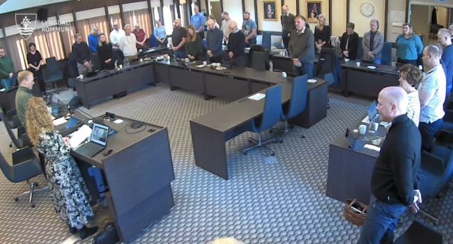 Bilde av kommunestyret som har reist seg for ett minutts stillhet