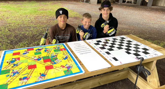 Bilde av de tre unge guttene og spillebordet de har laget