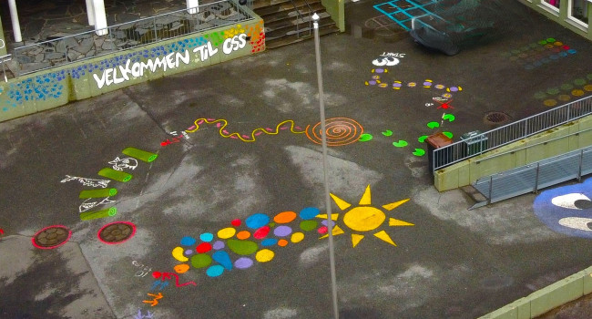 Dronefoto av fargerike tegninger på uteplassen ved Å barneskole