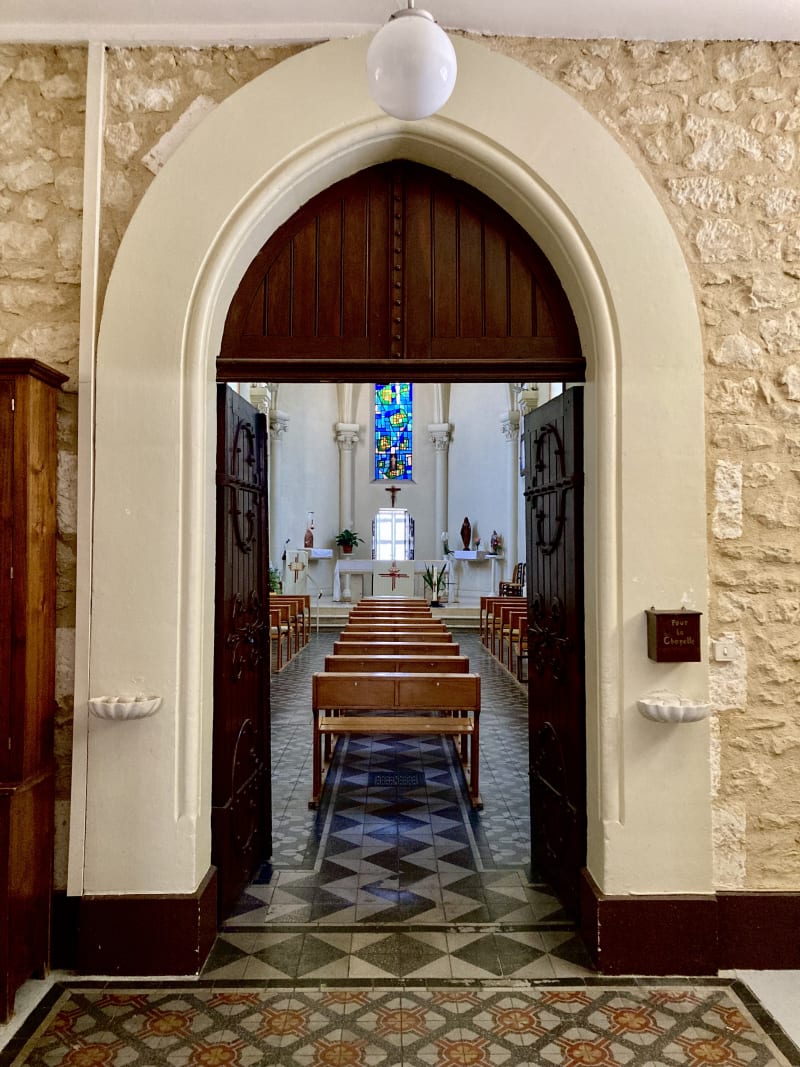 Une grande porte en bois, solennelle, menant au rez-de-chaussée de la chapelle.