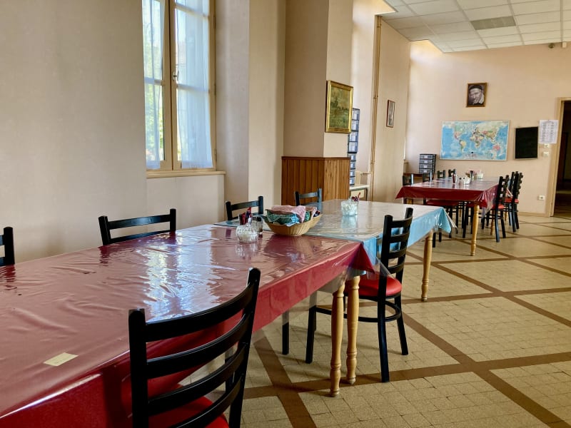 Vaste salle à manger avec plusieurs tables rectangulaires colorées accolées les unes aux autres.