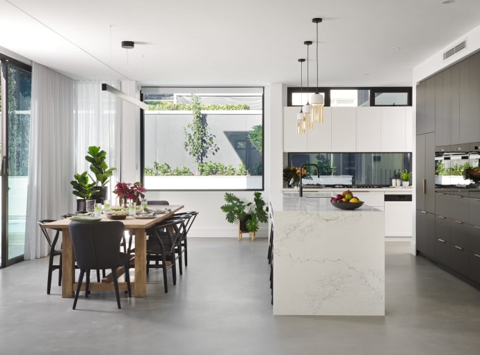 Open-plan living, dining and kitchen in a custom Perth home with polished concrete floors, marble island bench and glass doors to the garden.