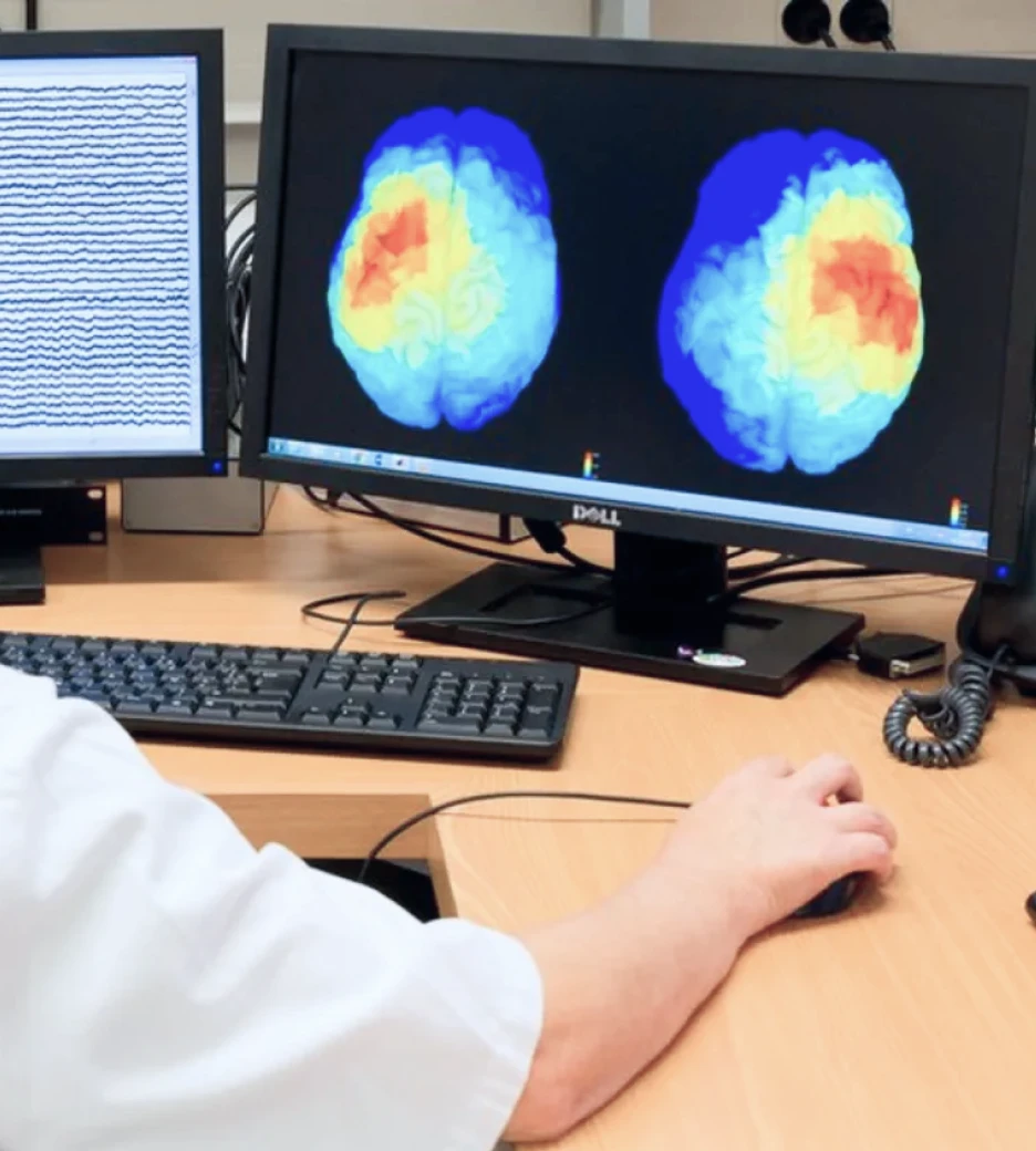 A researcher is shown working on a computer with two brain scans shown on the screen