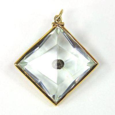 Mustard seed enclosed in crystal with solid 10K gold frame.
