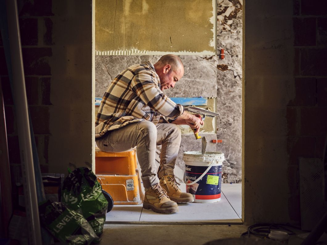 Tradie wearing safety boots sitting and mixing cement