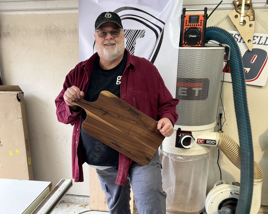 Man in red jacket holding wooden knife board