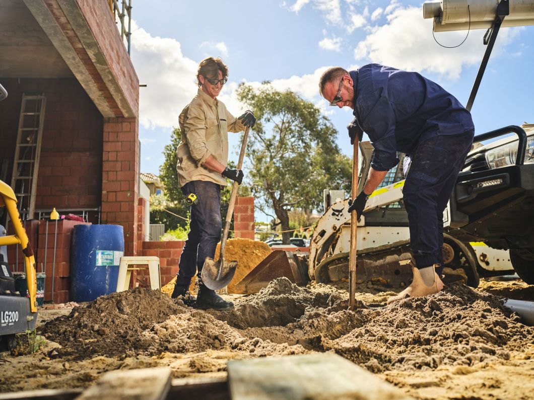 Builders digging into sand while wearing