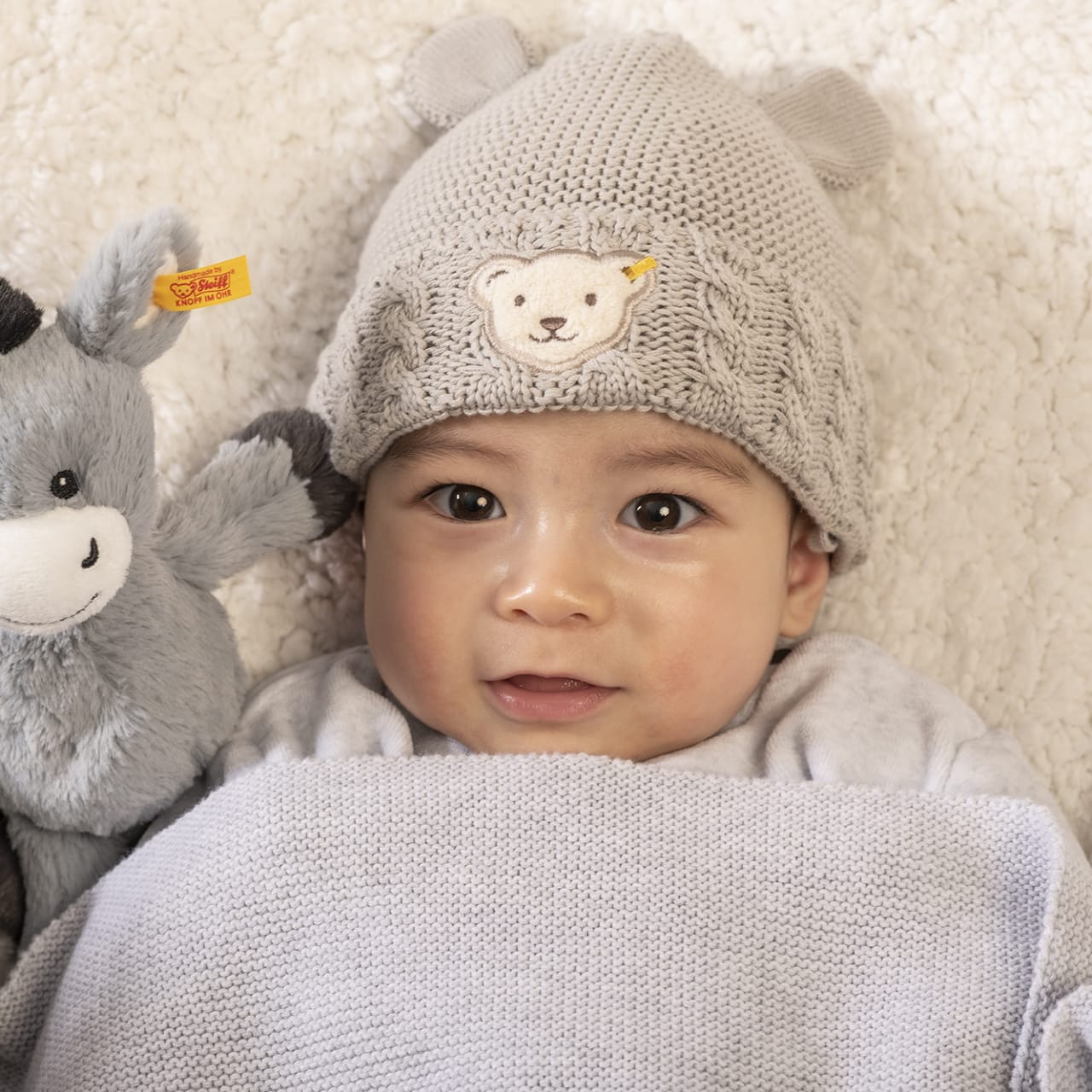 Baby mit steiff beanie und esel kuscheltier emo