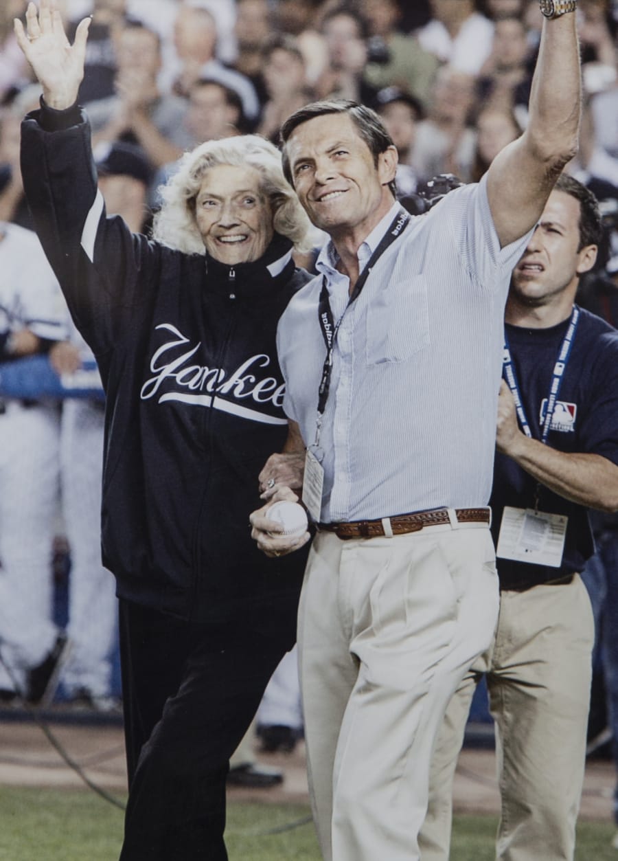 Julia Ruth Stevens and son Tom Stevens waving to fans before Ruth
                Stevens threw out the first pitch at the last game at the original Yankee Stadium.