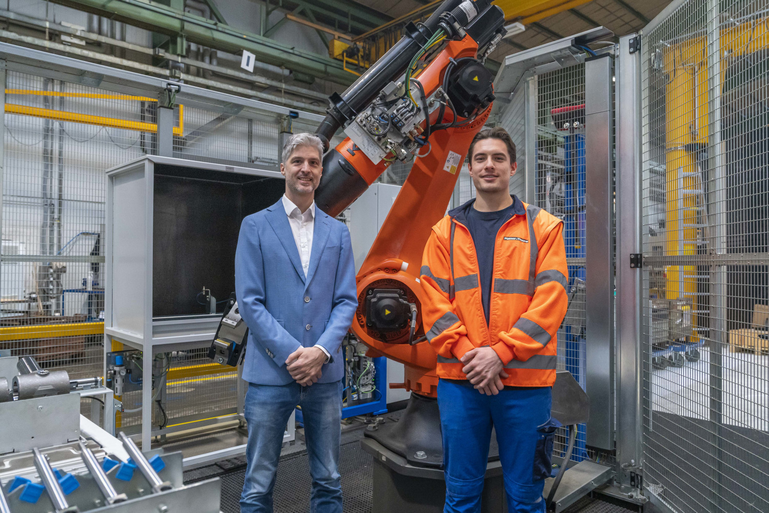 Zwei Personen stehen vor dem Bedienroboter und blicken zufrieden und optimistisch