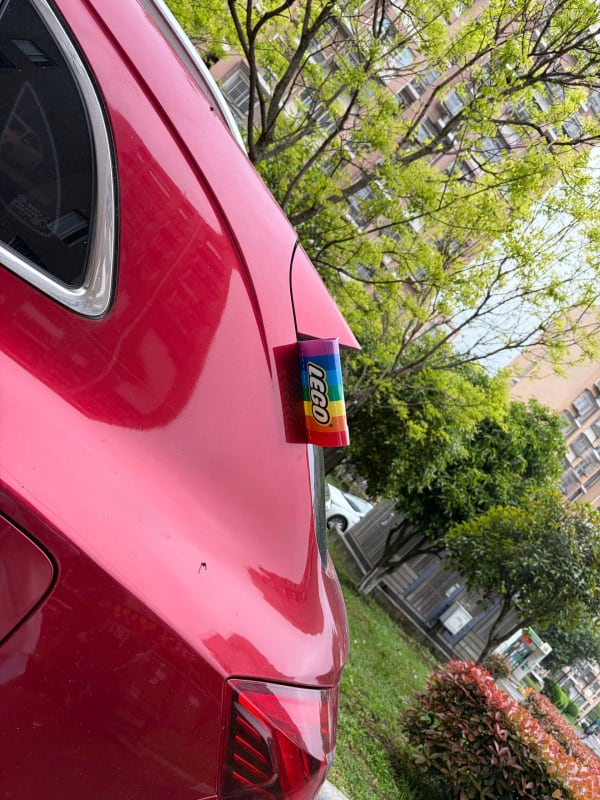 Rainbow tag attached to a red SUV, reading "LEGO"