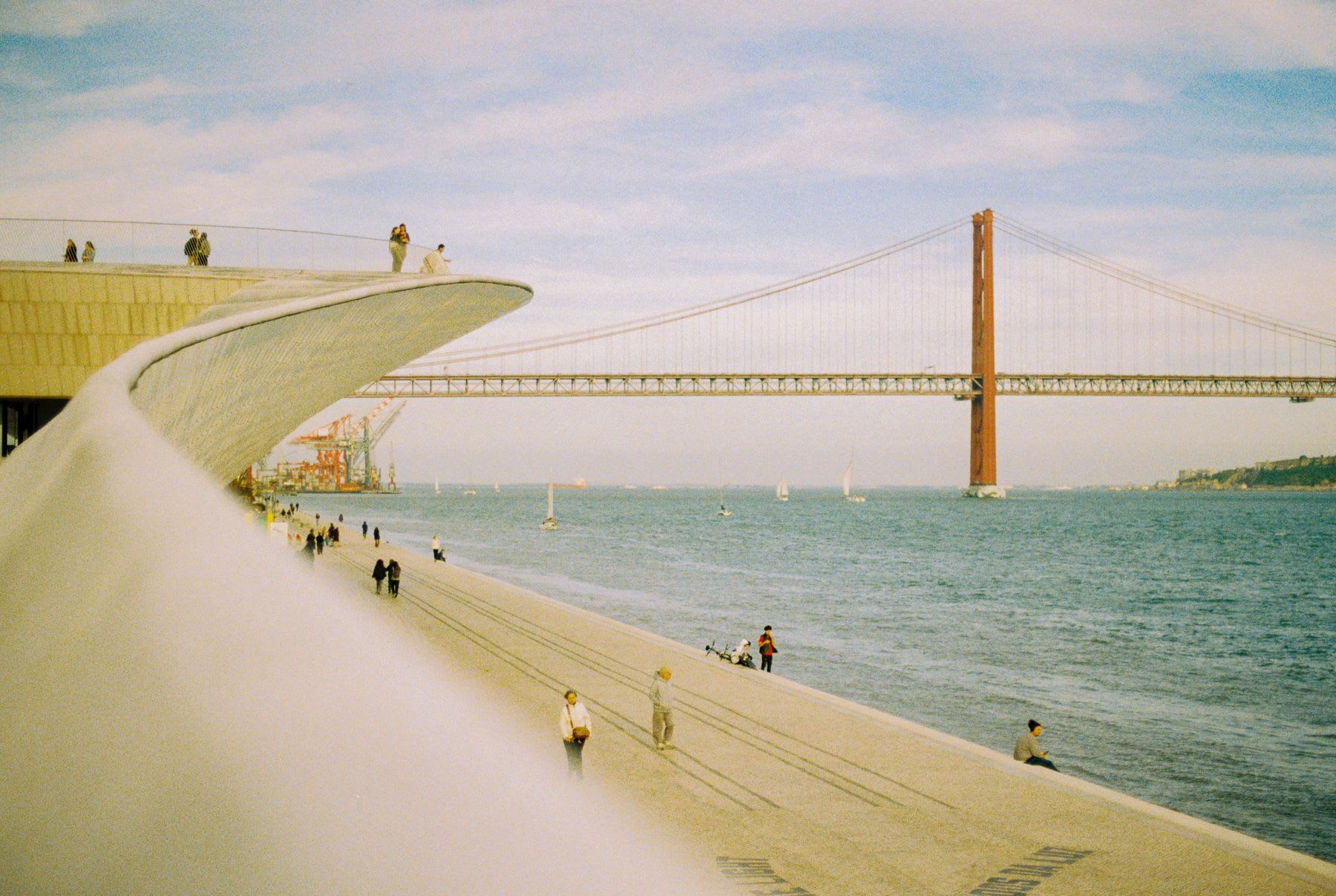 People enjoying the san francisco bay waterfront and the golden gate bridge on a cloudy day