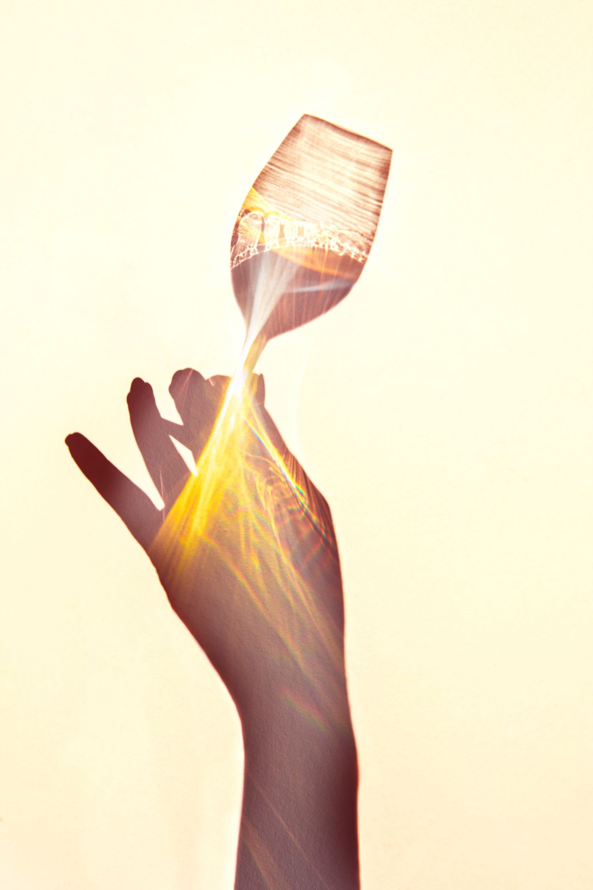 The shadow of a woman's hand holding up a wine glass.