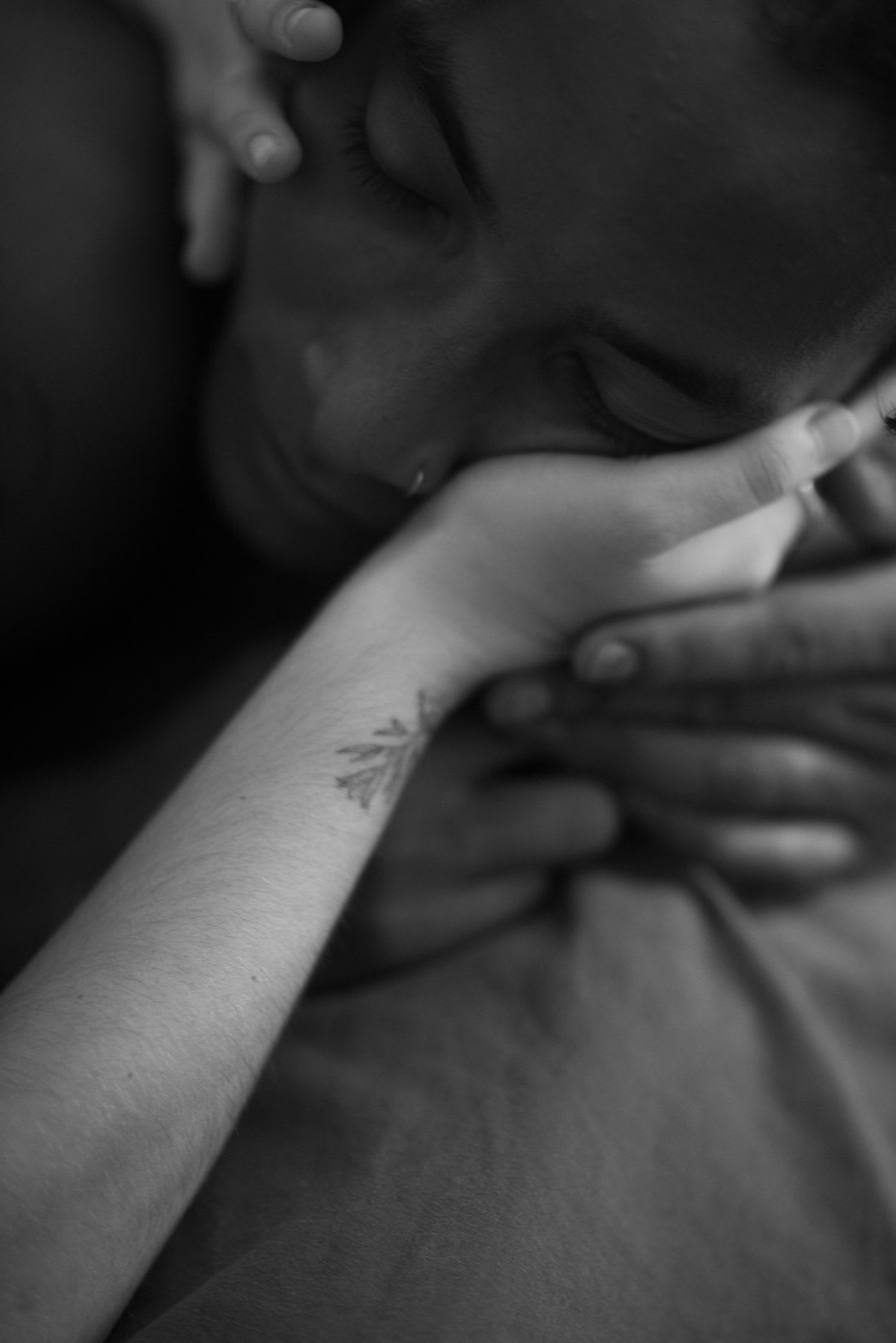An intimate moment, with a person resting with their eyes closed, caressed by gentle hands.