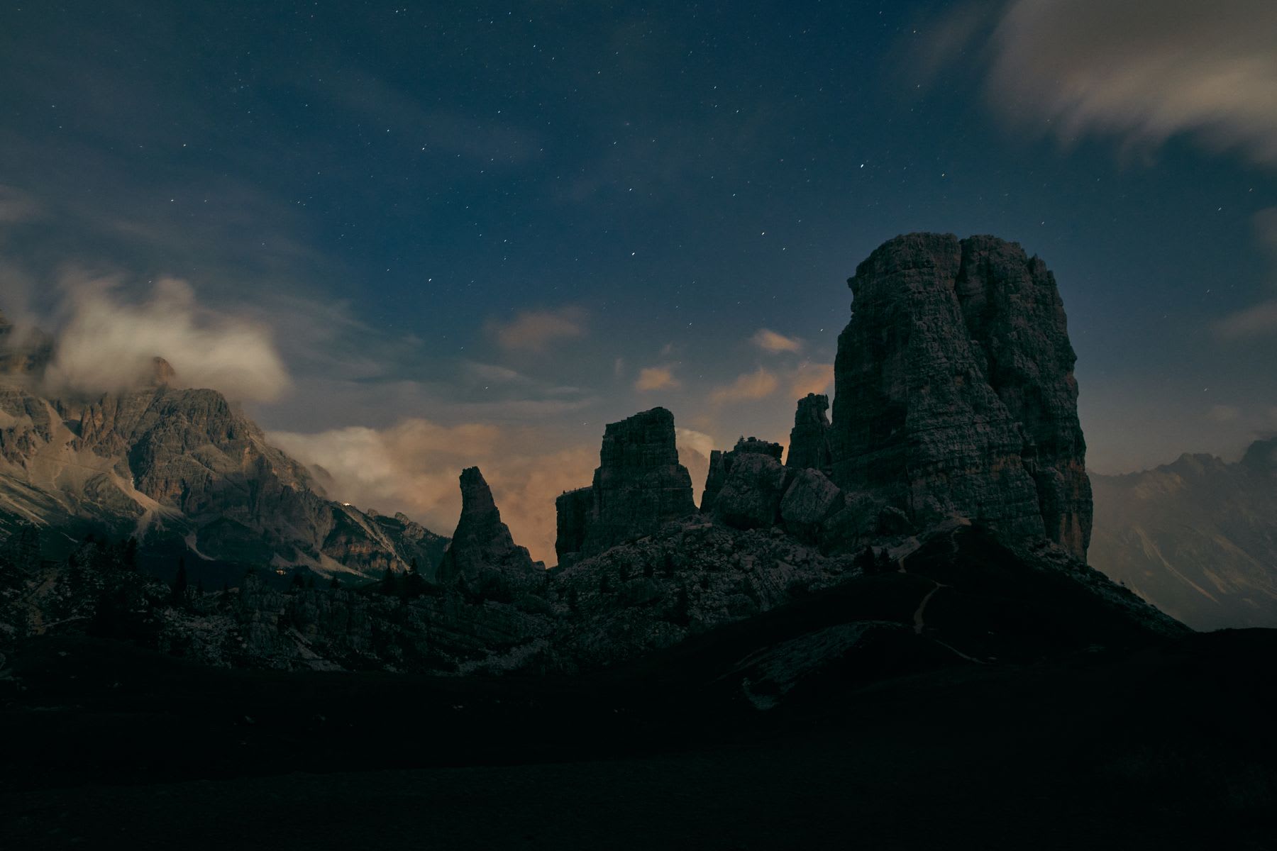 Giant rock formations stand near the top of a rocky mountain range at sunset.