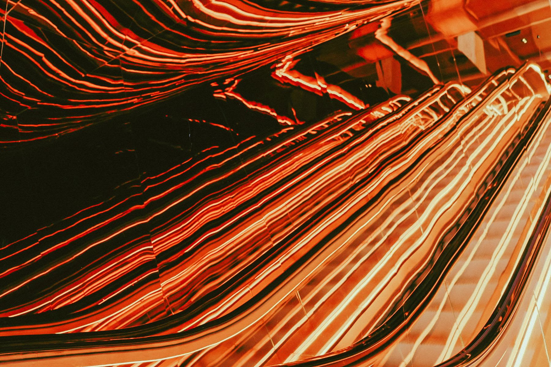 Vibrant reflections of lights on a dark surface, creating a fluid and dynamic pattern of red lines.
